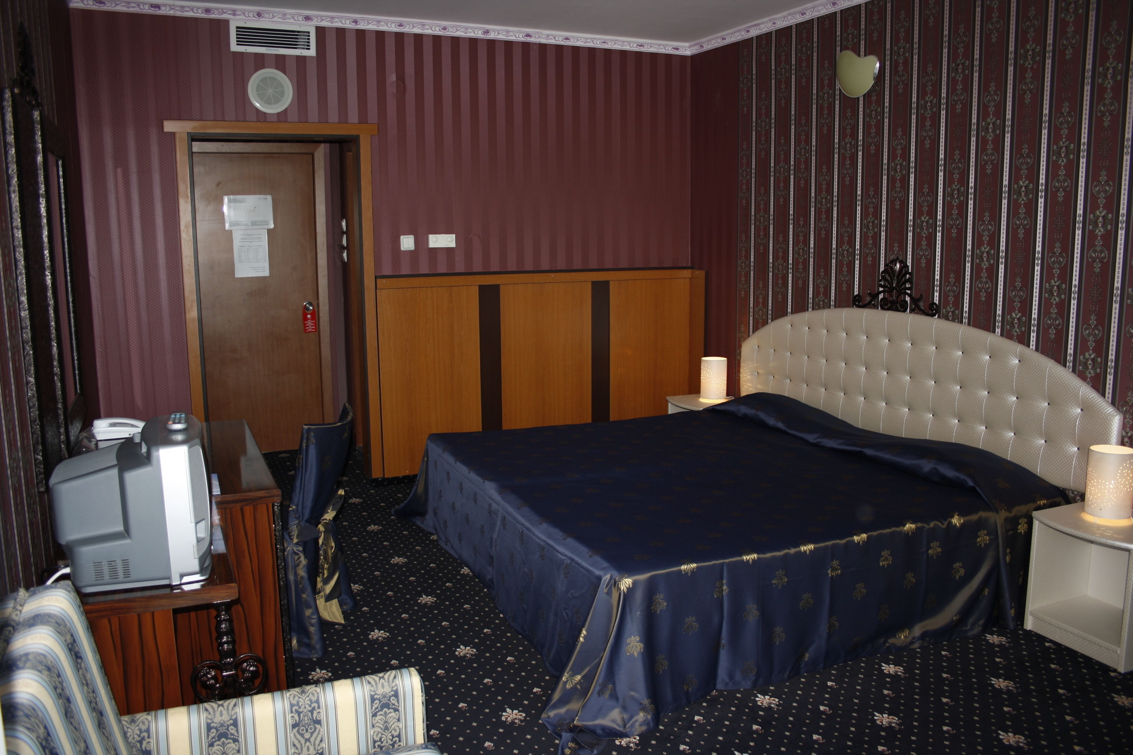 A hotel room with a bed, a television, a desk, and a nightstand.