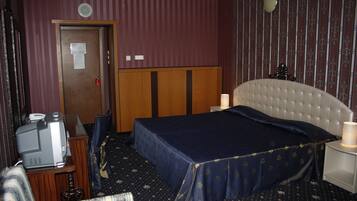 A hotel room with a bed, a television, a desk, and a nightstand.
