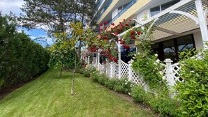 Un hotel con un jardín cuidado, valla de piquete blanca y un edificio con balcones.