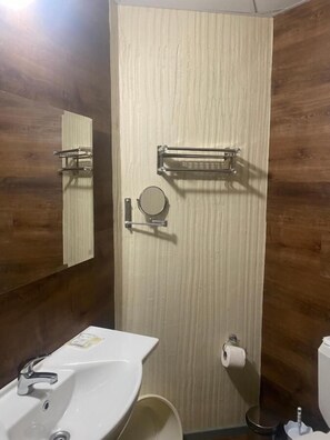 A bathroom with a wooden wall, a sink, a toilet, and a mirror. - Hotel Sunset (Sunny Beach)