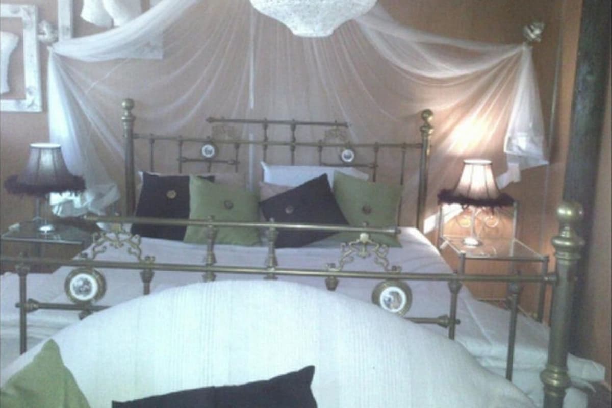 A bed with a canopy, bedside lamps, and a bedside table.
