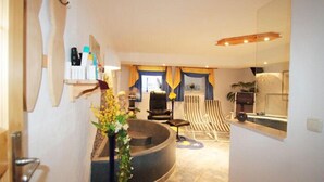 A hotel lobby with a reception desk, a seating area with chairs, a small pool, and a decorative plant. - Schmuckenhof (Marktschellenberg)