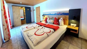 A bedroom with a large bed, wooden ceiling, and a mountain view painting. - Schmuckenhof (Marktschellenberg)