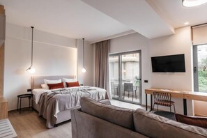 A modern bedroom with a bed, a desk, and a television. - The City Hotel & Suites (Rethymno)