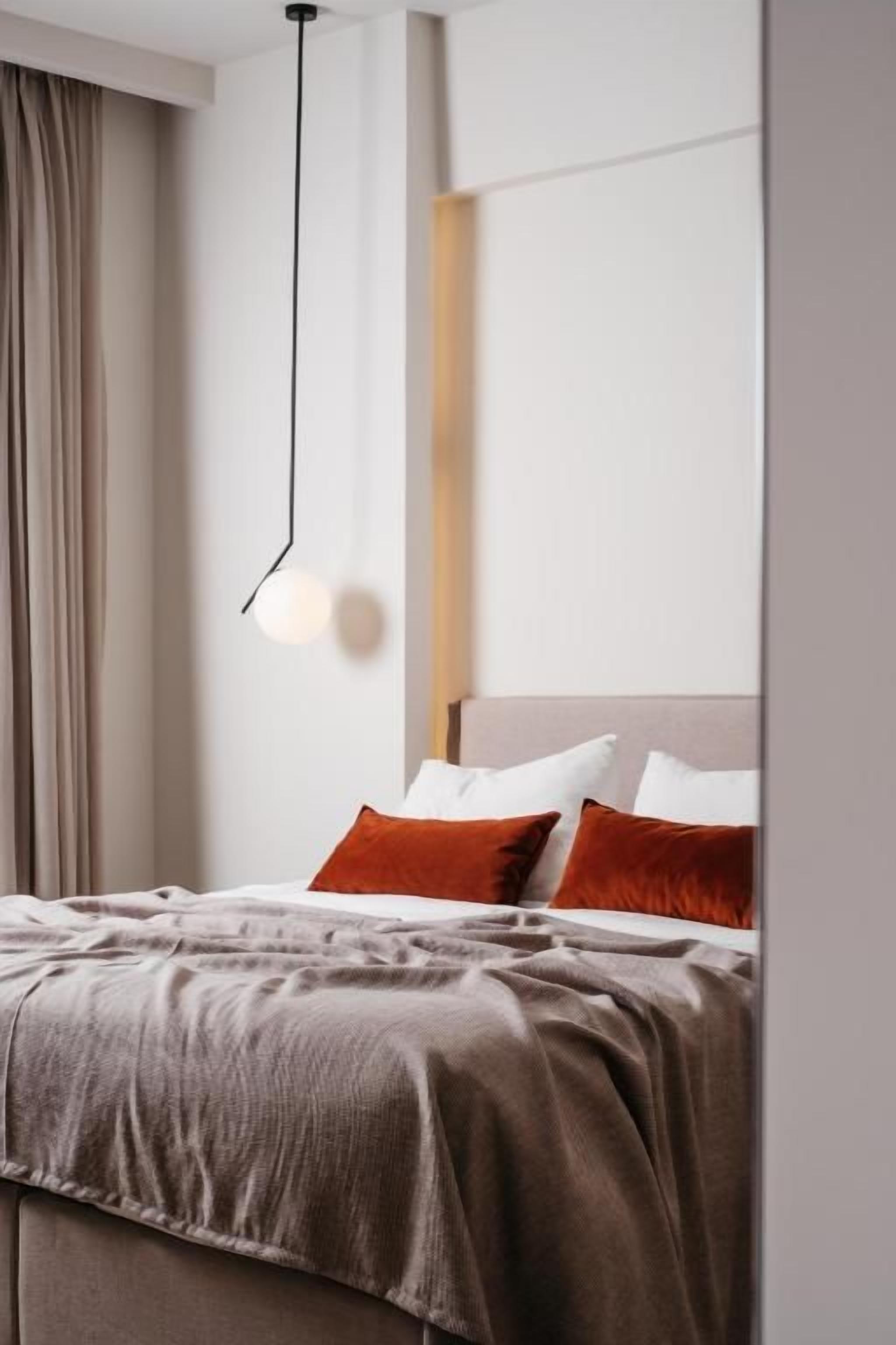A hotel room with a bed, a hanging light fixture, and a view of the outside.
