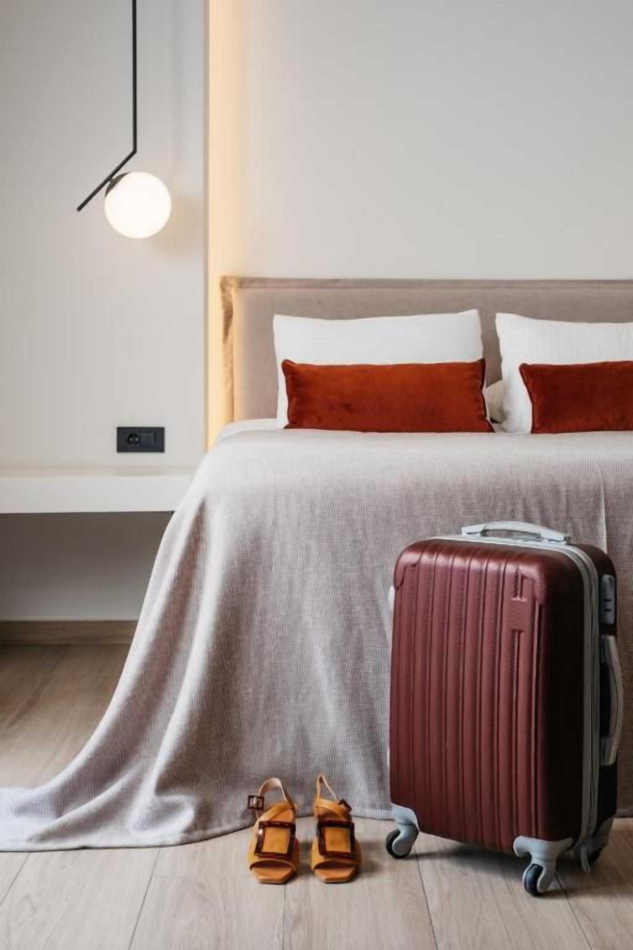 A bed with a headboard, a suitcase, and a pair of sandals on the floor.