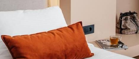 Una habitación de hotel con una cama, una mesita de noche con una lámpara, un bolso y una taza.