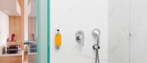 A modern bathroom with a glass shower enclosure, a handheld showerhead, and a wall-mounted faucet.
