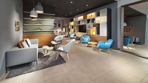 A modern interior with a sofa, chairs, a bookshelf, and a dining area. - Clarion Hotel Vienna South (Vienna)