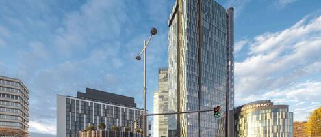 Un edificio moderno con fachada de vidrio curva, una entrada destacada con toldo y un letrero visible de 'IMMOFINANZ'.