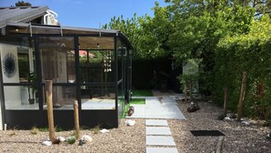 A modern glass structure with a gravel path leading to a green lawn. - Bungelow "Duinvogel" Beach with bath in the garden (Noordwijk)