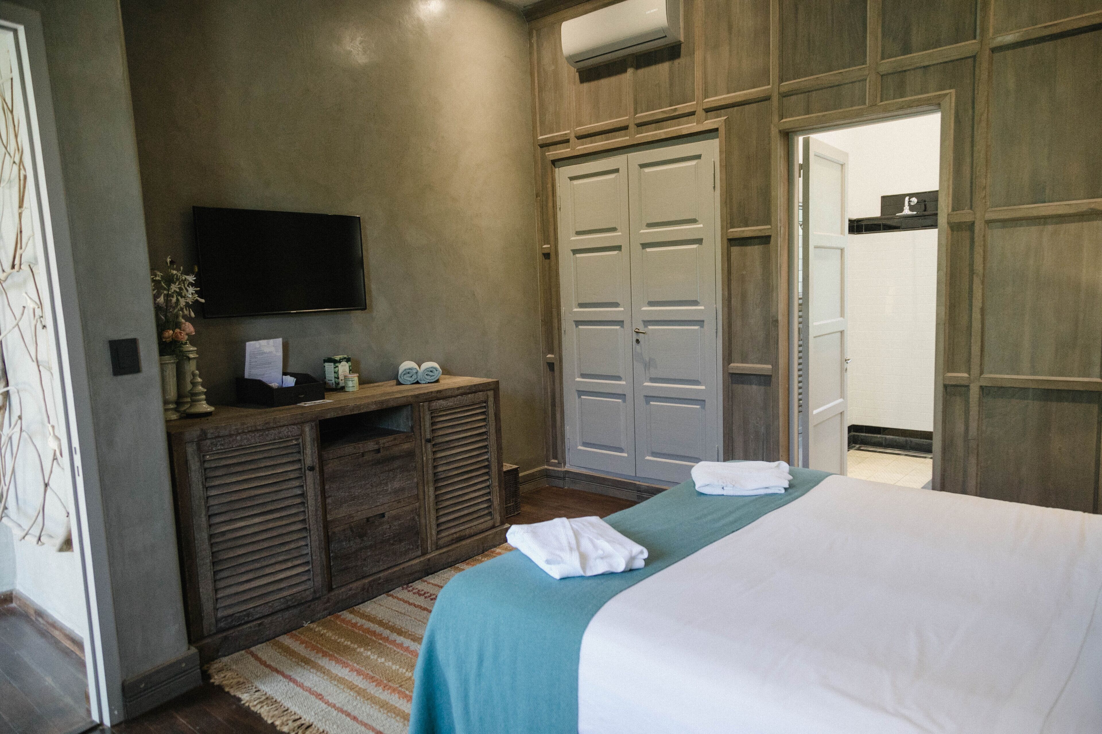 Een slaapkamer met een bed, een televisie, een houten dressoir en een kledingkast.