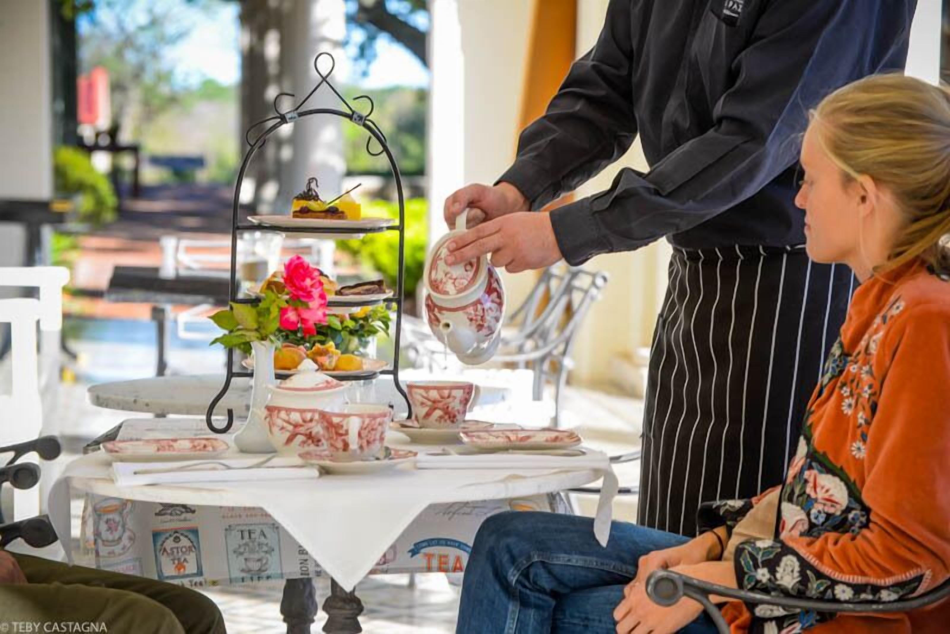 A tea service setup with a tiered stand, teapot, cups, and saucers on a table.