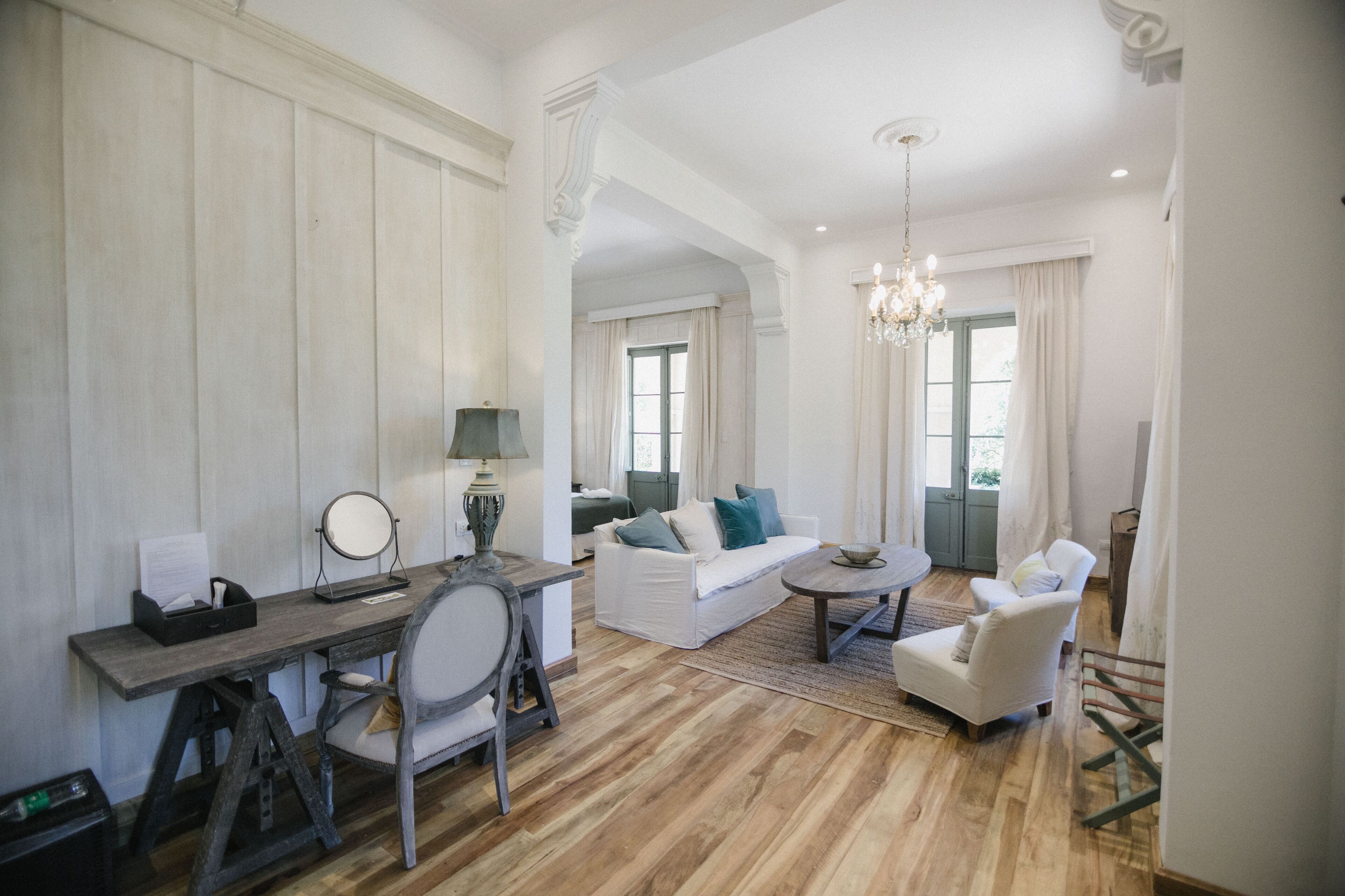 A spacious living room with a wooden floor, a white sofa, a coffee table, and a dining area with a wooden table and chairs.