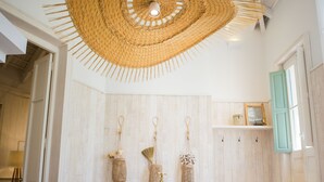 Une salle de bain avec deux lavabos, un grand luminaire suspendu en fibres tressées et des murs recouverts de panneaux en bois.