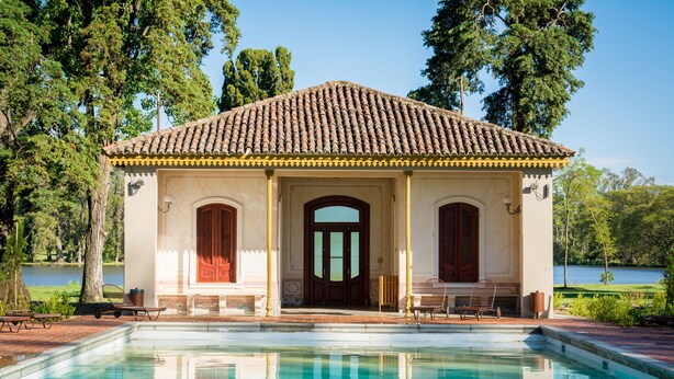 Un bâtiment avec un toit en tuiles, une piscine et une vue sur un lac.