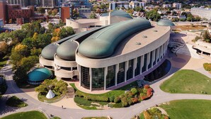 A modern building with a unique curved roof and multiple domes, surrounded by landscaped gardens and a paved walkway. - Holiday Inn Express & Suites Downtown Ottawa East by IHG (Ottawa)