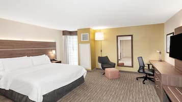 Une chambre d’hôtel avec un grand lit, un bureau, une chaise, une télévision et une lampe.