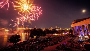 A large outdoor venue with a crowd, a body of water, and a building with a dome and large windows. - Holiday Inn Express & Suites Downtown Ottawa East by IHG (Ottawa)