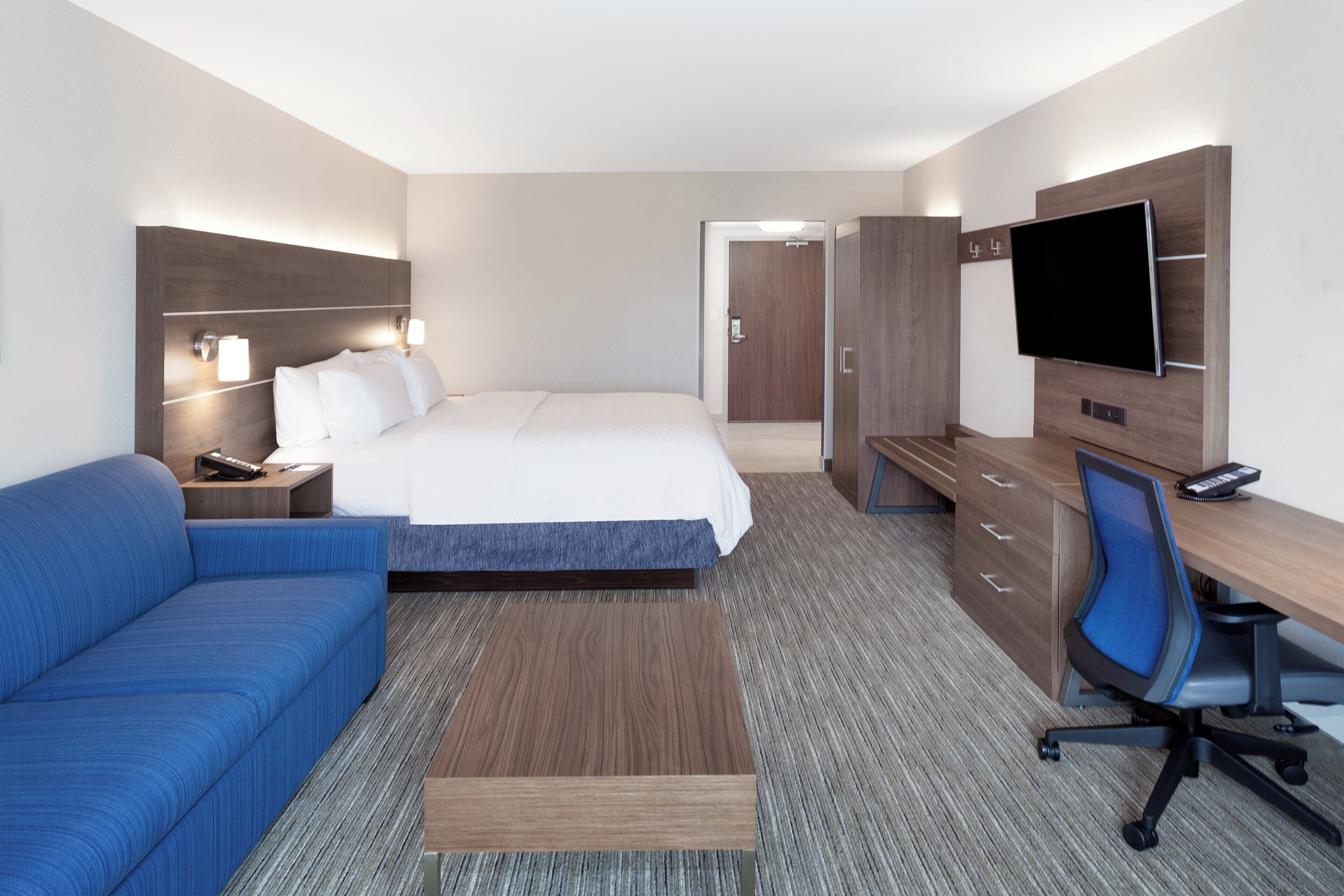 Una habitación de hotel con cama, escritorio, silla, sofá y televisor.
