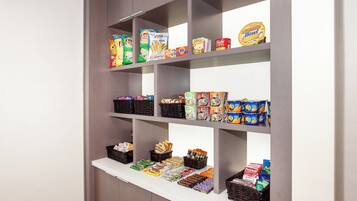 Una despensa con estantes llenos de diversos alimentos, entre ellos aperitivos, conservas y productos envasados.
