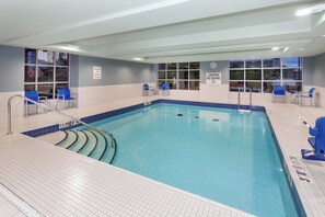 A swimming pool with blue tiles, a lifeguard chair, and a caution sign.