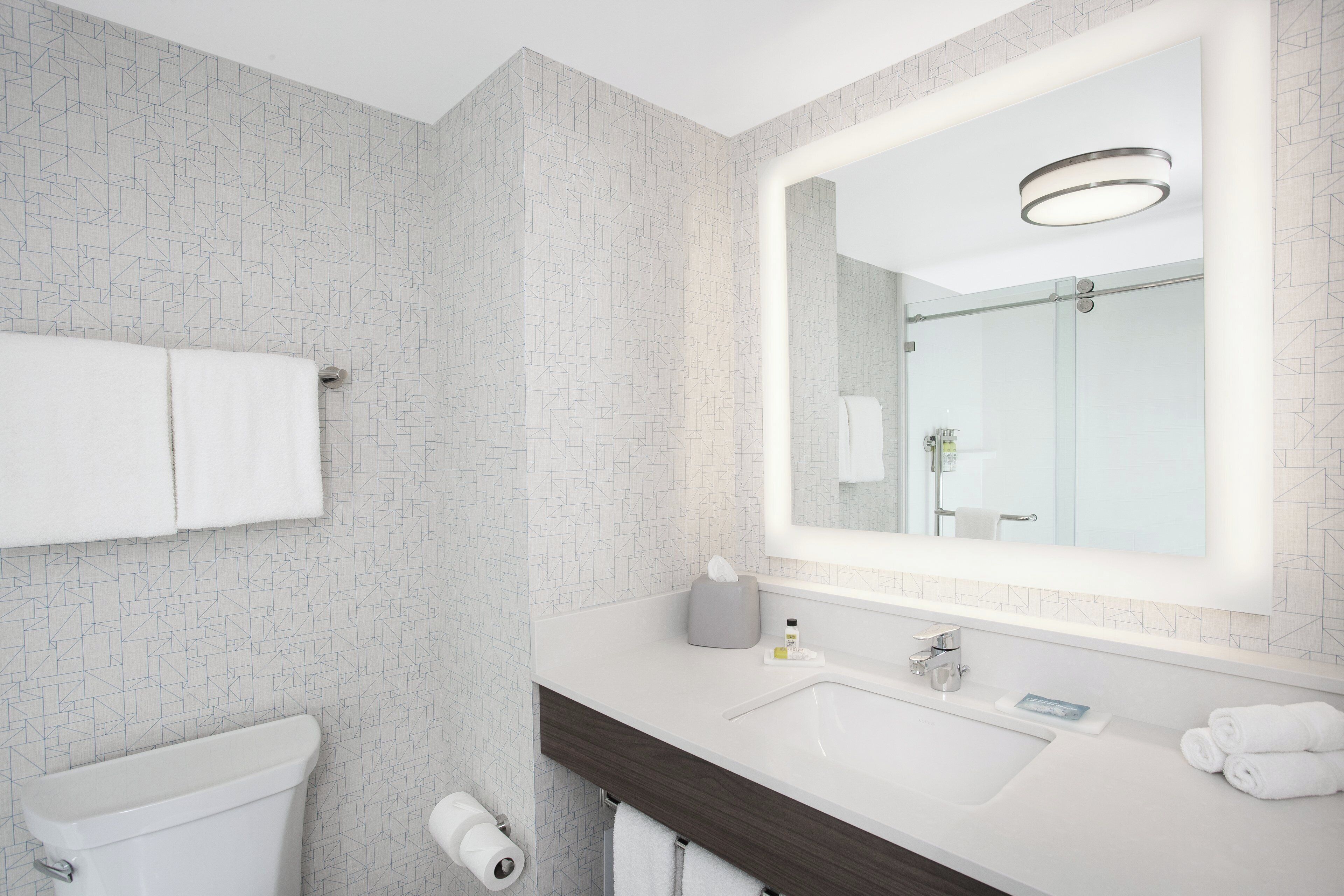 Een moderne badkamer met een wit toilet, een wastafel met spiegel en een handdoekrek.
