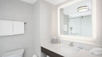 Une salle de bain moderne avec des toilettes blanches, un lavabo avec un miroir et un porte-serviettes.