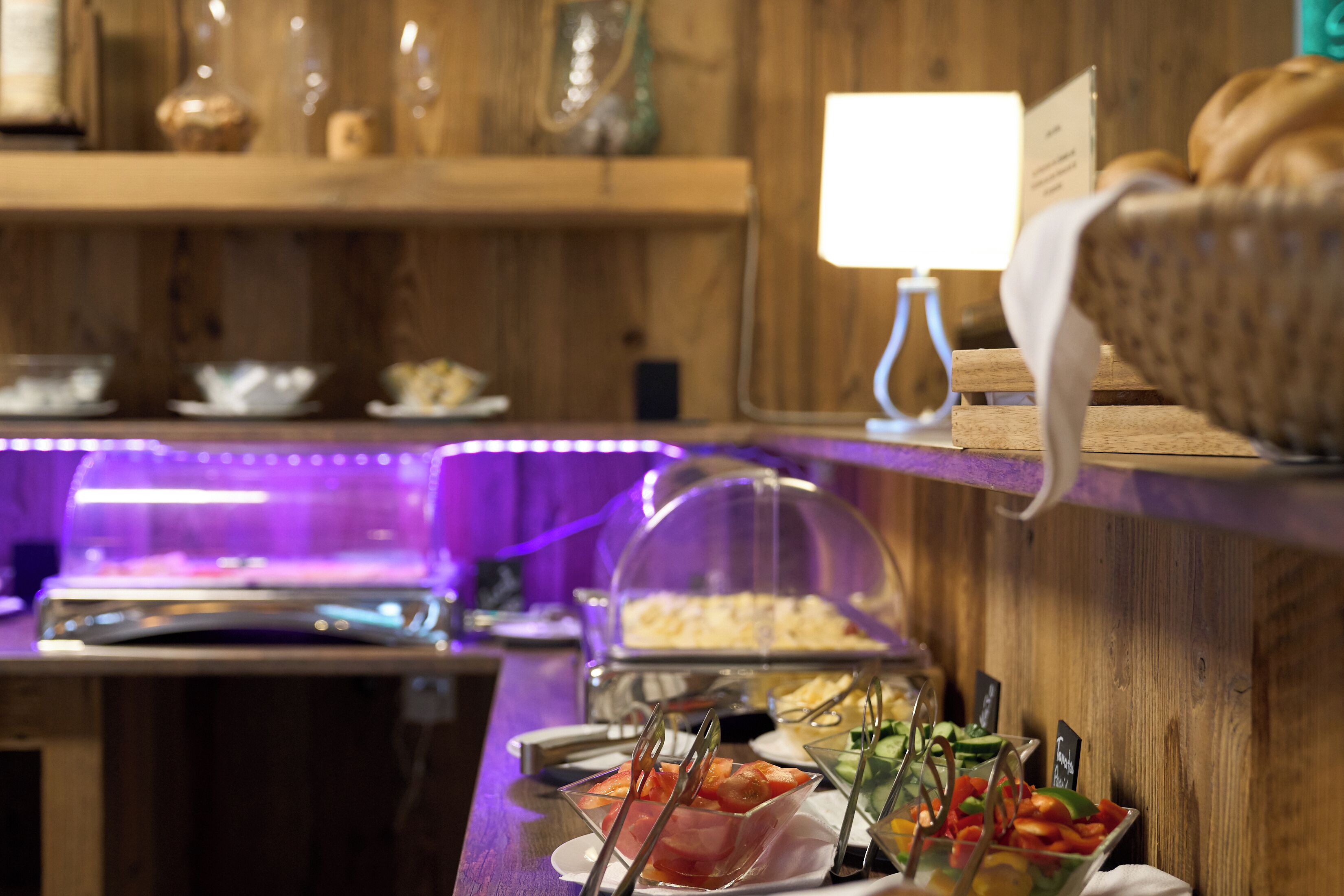 Un buffet allestito con diversi cibi e un contenitore di vetro trasparente.