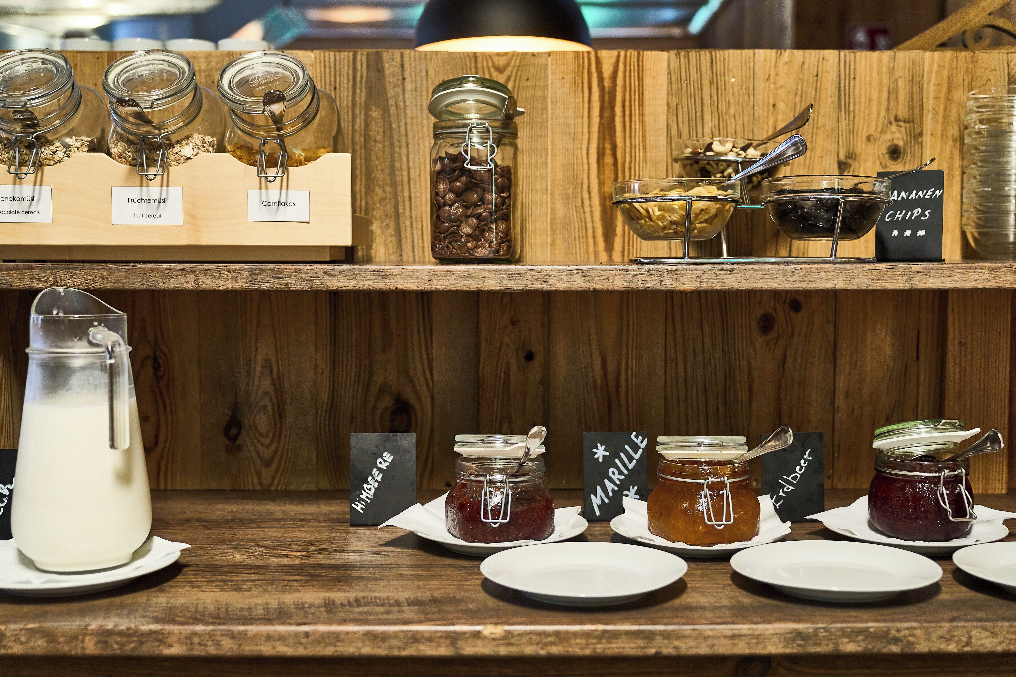 Una barra de madera con diversos alimentos y condimentos, incluyendo frascos etiquetados con nombres como "Chokomojiru" y "Marile".