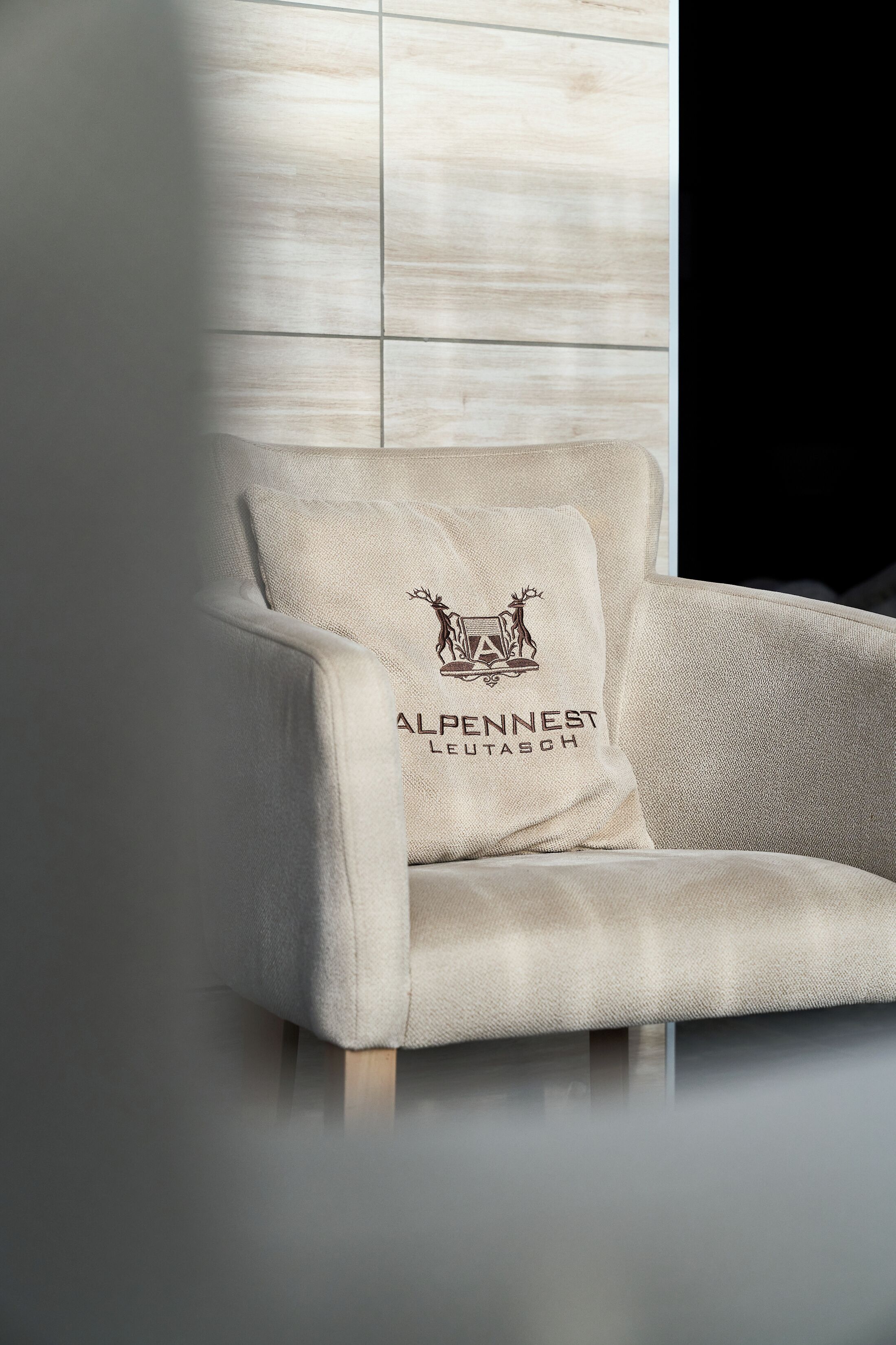 A beige armchair with a logo and text on the backrest.
