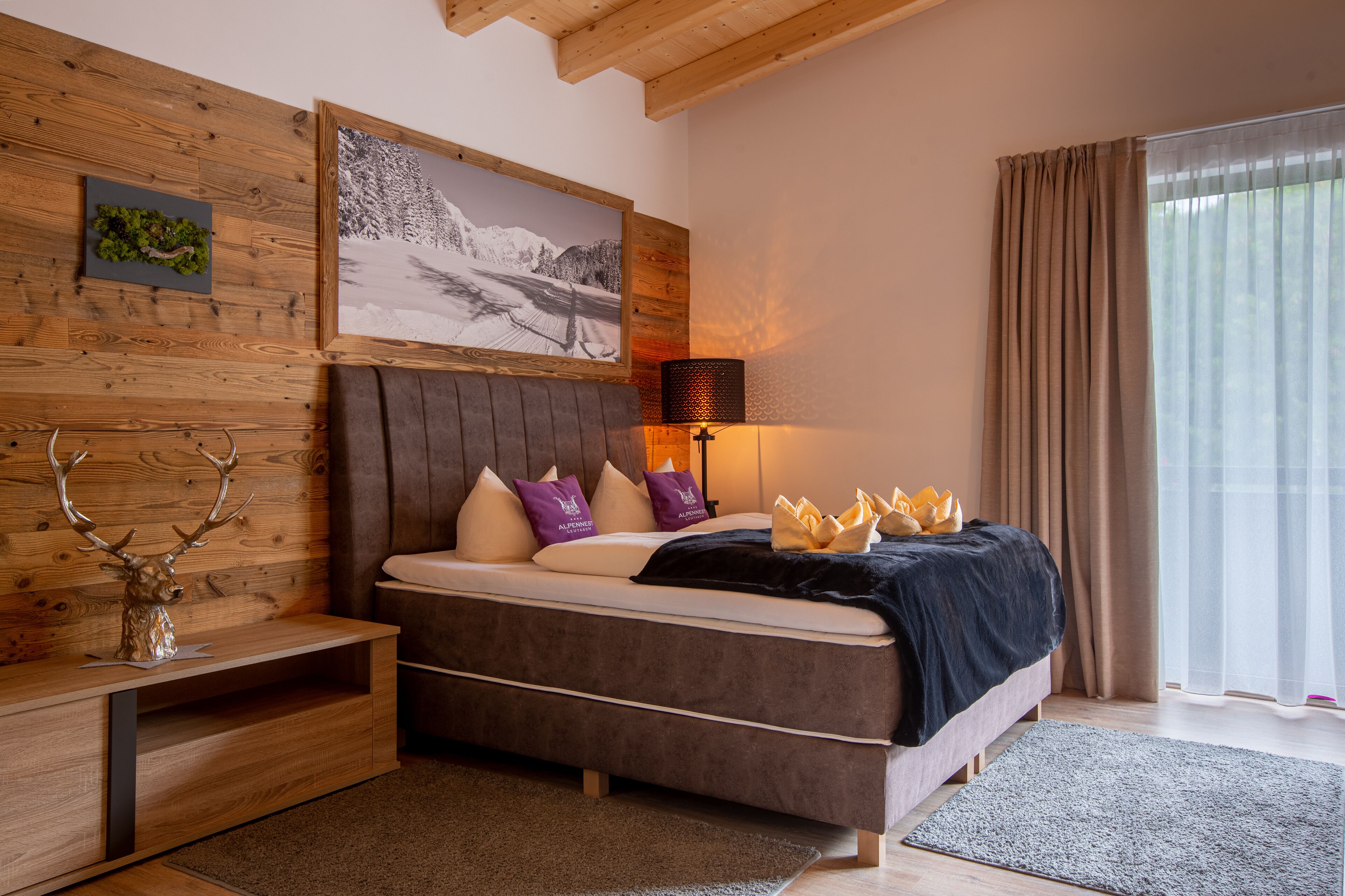 A bedroom with a bed, wooden headboard, a nightstand, a lamp, and a painting on the wall.