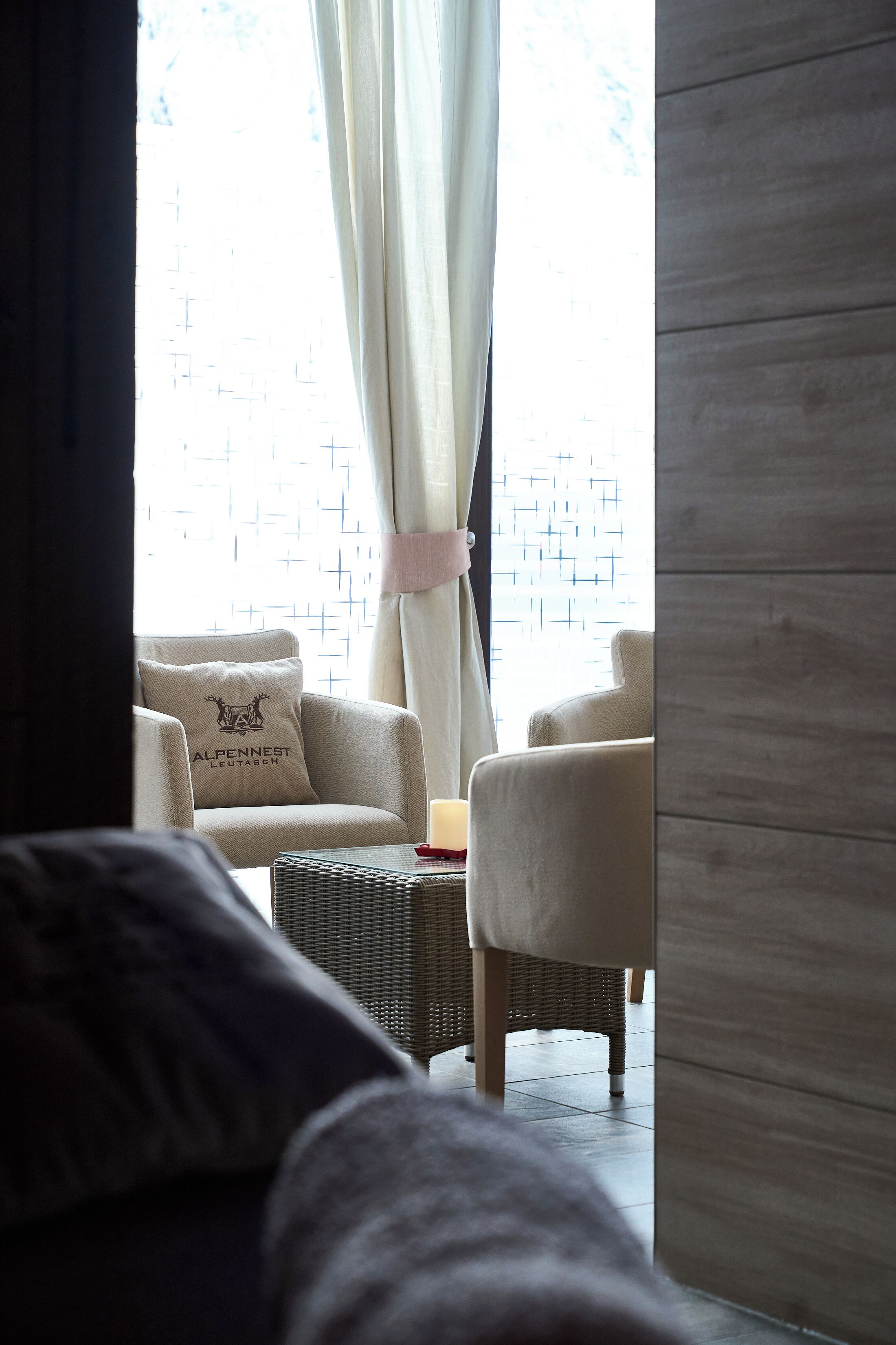 Una habitación con vistas a través de una ventana, que incluye un sofá, una silla y una mesita.