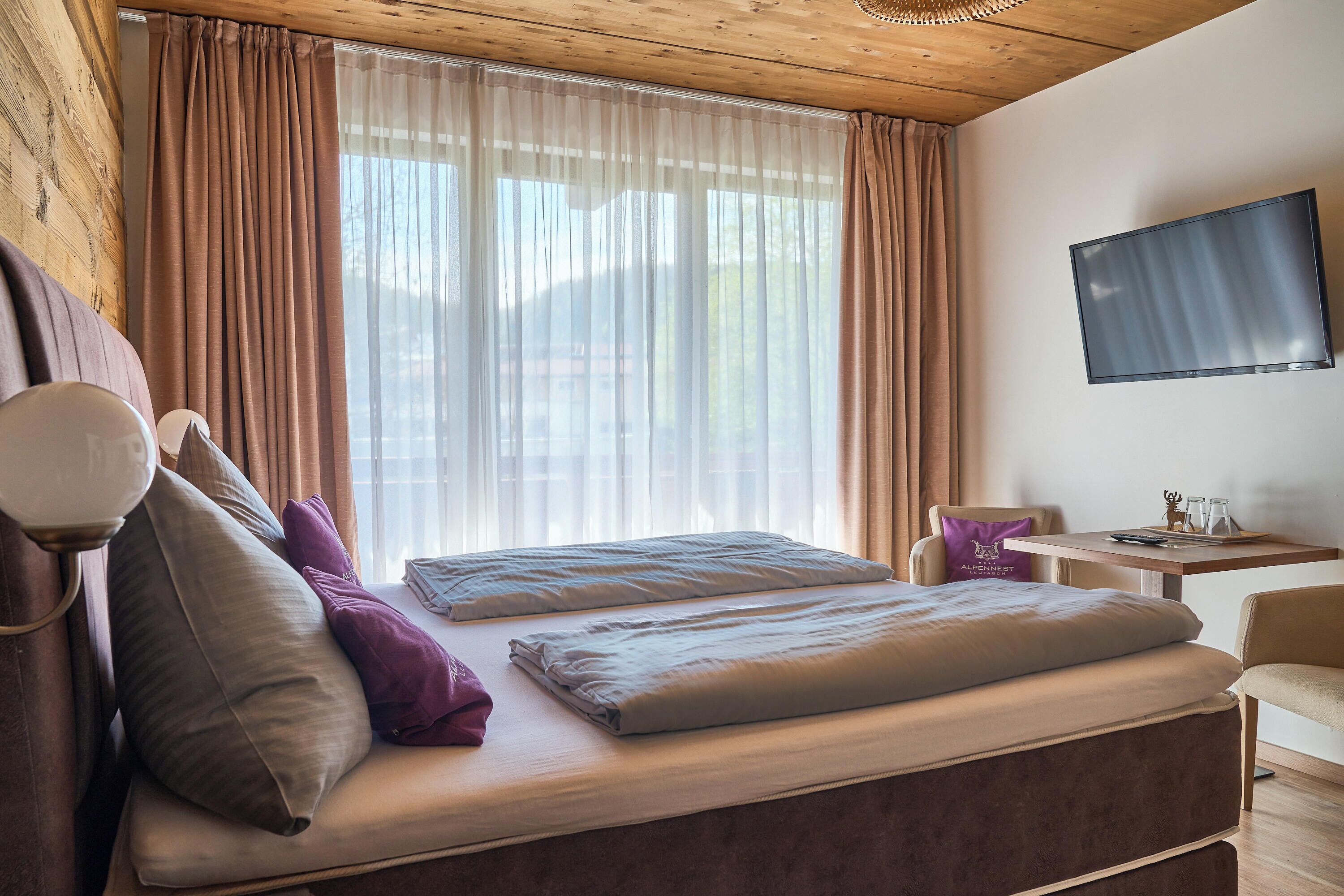 Een slaapkamer met een bed, een televisie, een tafeltje en een stoel.