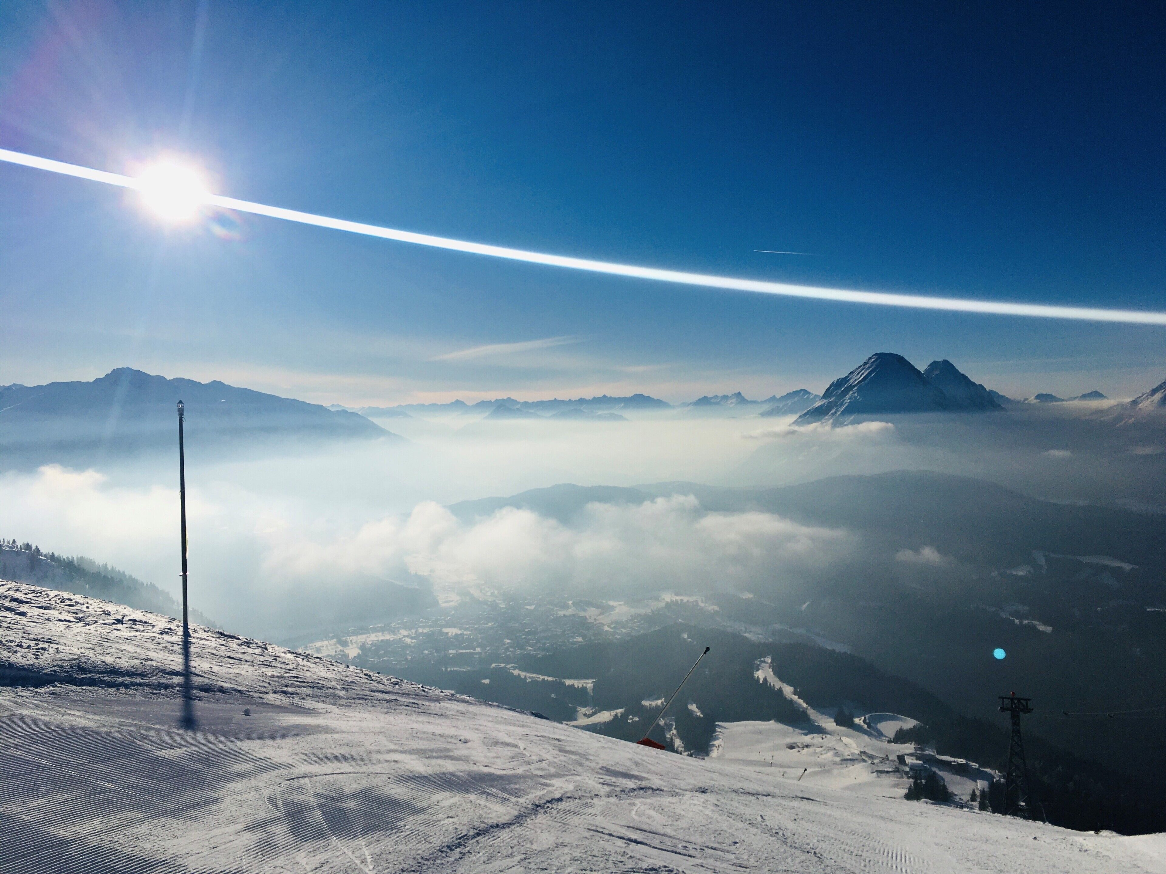 A snowy mountain landscape with a clear sky, a ski slope, and a distant mountain peak.