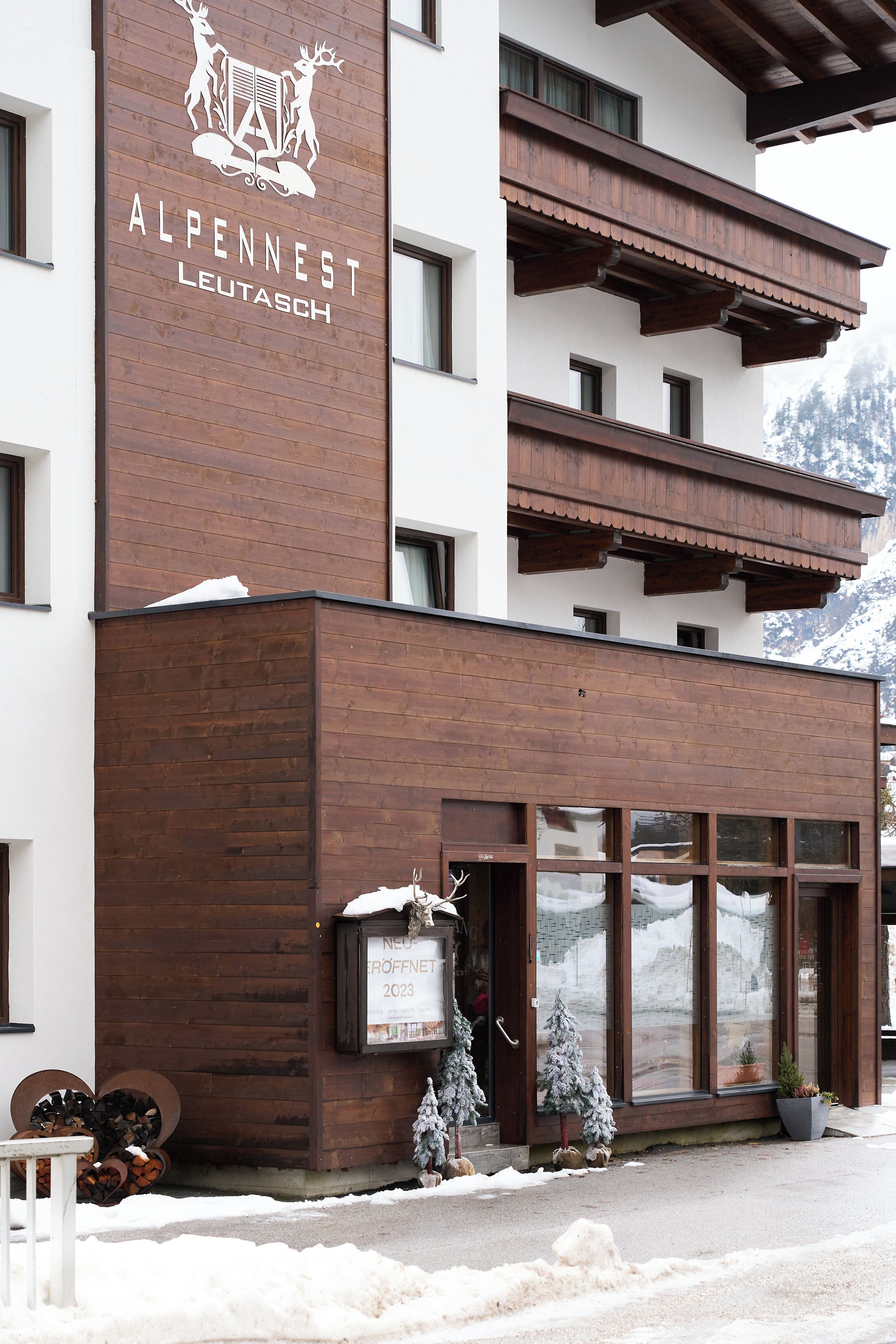 Un hotel llamado Alpennest Leutatsch con diseño moderno, que presenta fachada de madera y ventanas grandes.