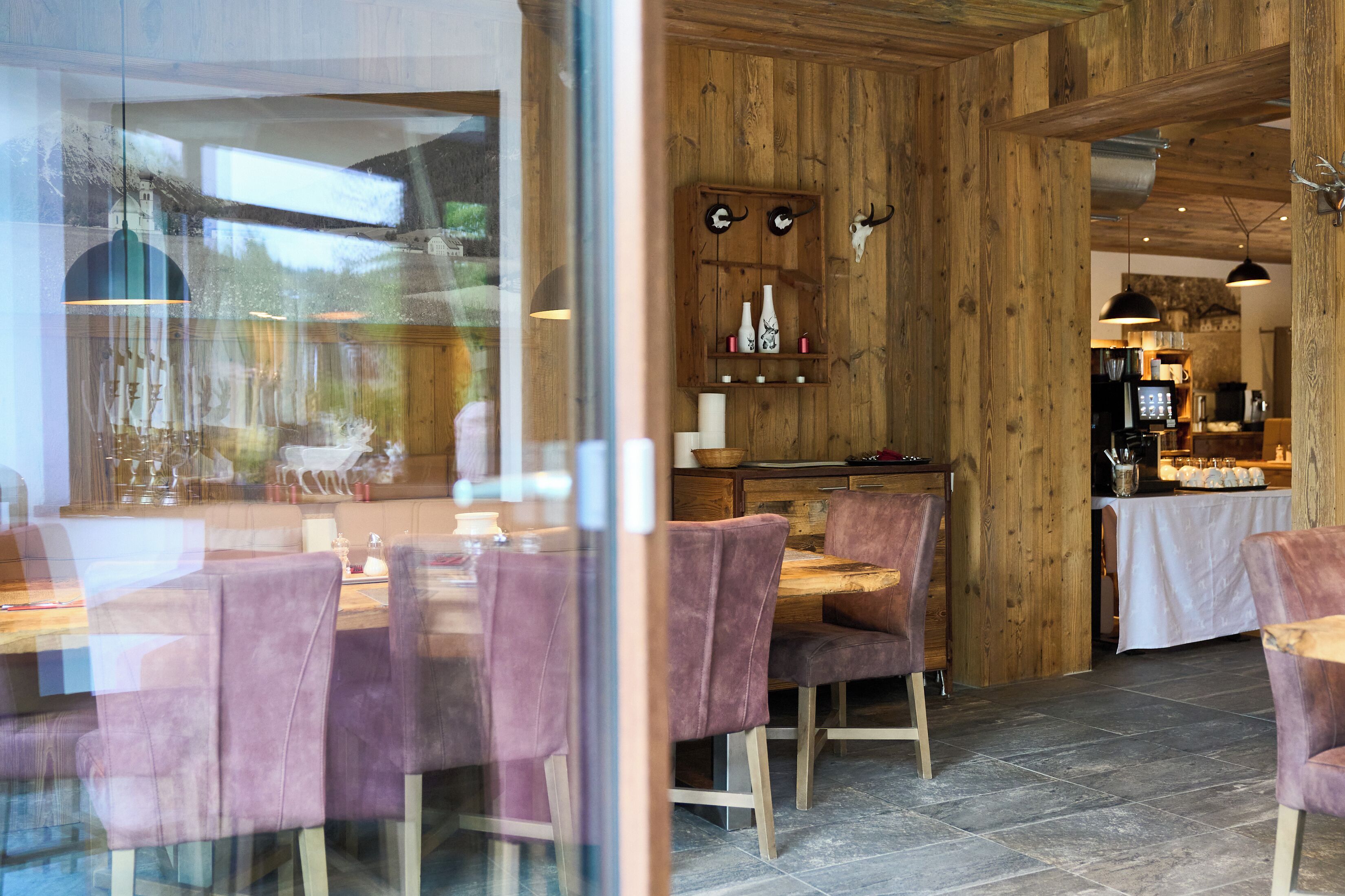A restaurant with wooden walls, a dining area with purple chairs, and a kitchen in the background.