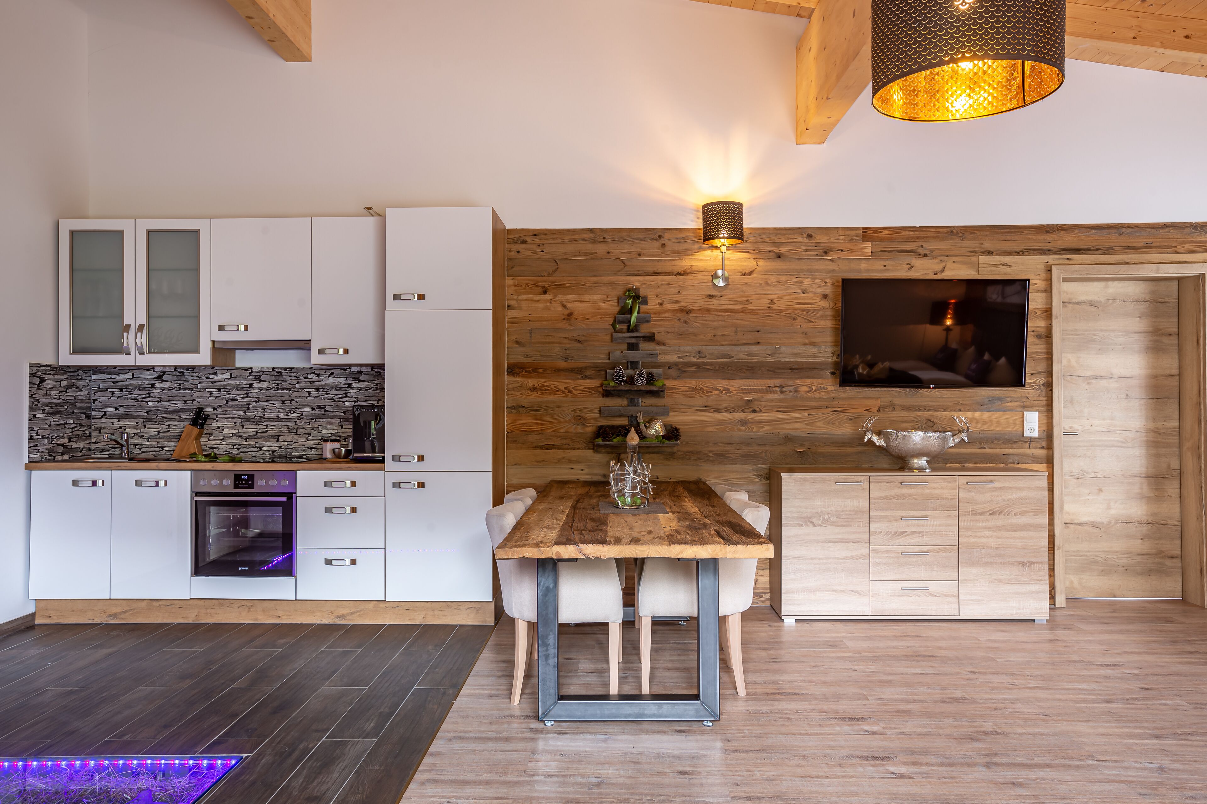 A modern kitchen with white cabinets, a stone backsplash, and a wooden dining table with chairs.