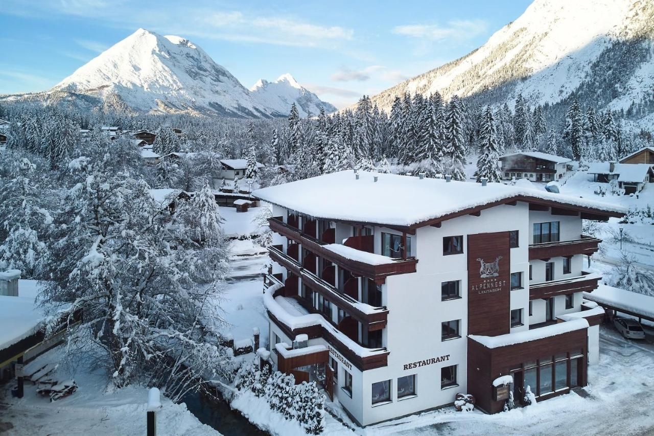 A multi-story building with a restaurant sign, surrounded by snow-covered trees and mountains.