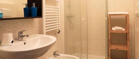 A modern bathroom with a glass-enclosed shower, a white sink, and a toilet.