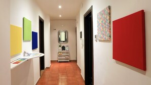 A hallway with white walls, a tiled floor, and artwork on the walls. - Bari Primo Piano (Bari)