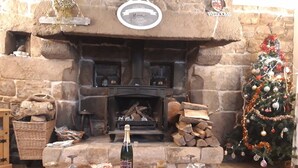 A cozy room with a stone fireplace, a Christmas tree, and a table set for a meal. - ---------Chestnut - La Châtaigne----------- (Langoëlan)