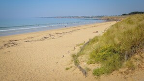 A sandy beach with a wooden fence and grass on the right. - ---------Chestnut - La Châtaigne----------- (Langoëlan)