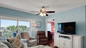 Una sala de estar con ventilador de techo, televisor y vista al exterior.