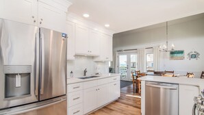 A modern kitchen with stainless steel appliances, white cabinetry, and a wooden floor.