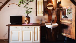 A bathroom with a wooden vanity, a sink, a mirror, and a television on a cabinet. - Alte Kass Hotel und Kaffeehaus (Neidlingen)
