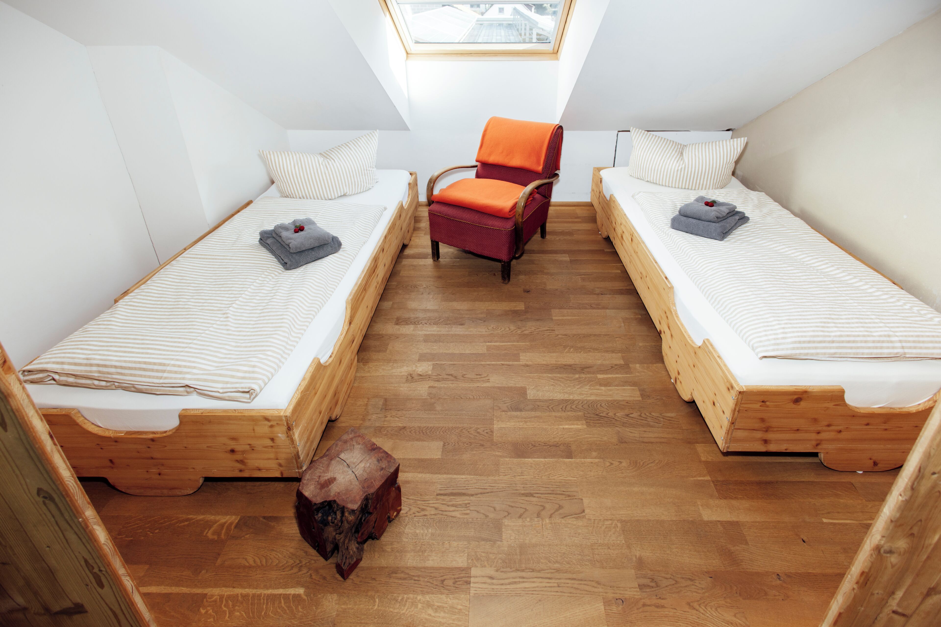 Un petit logement composé d’une seule pièce, comprenant deux lits superposés en bois, une chaise en bois et un puits de lumière.