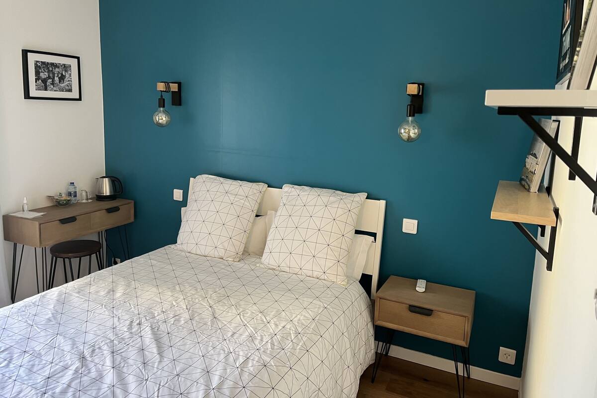 Un dormitorio con cama, mesitas de noche, escritorio y silla.