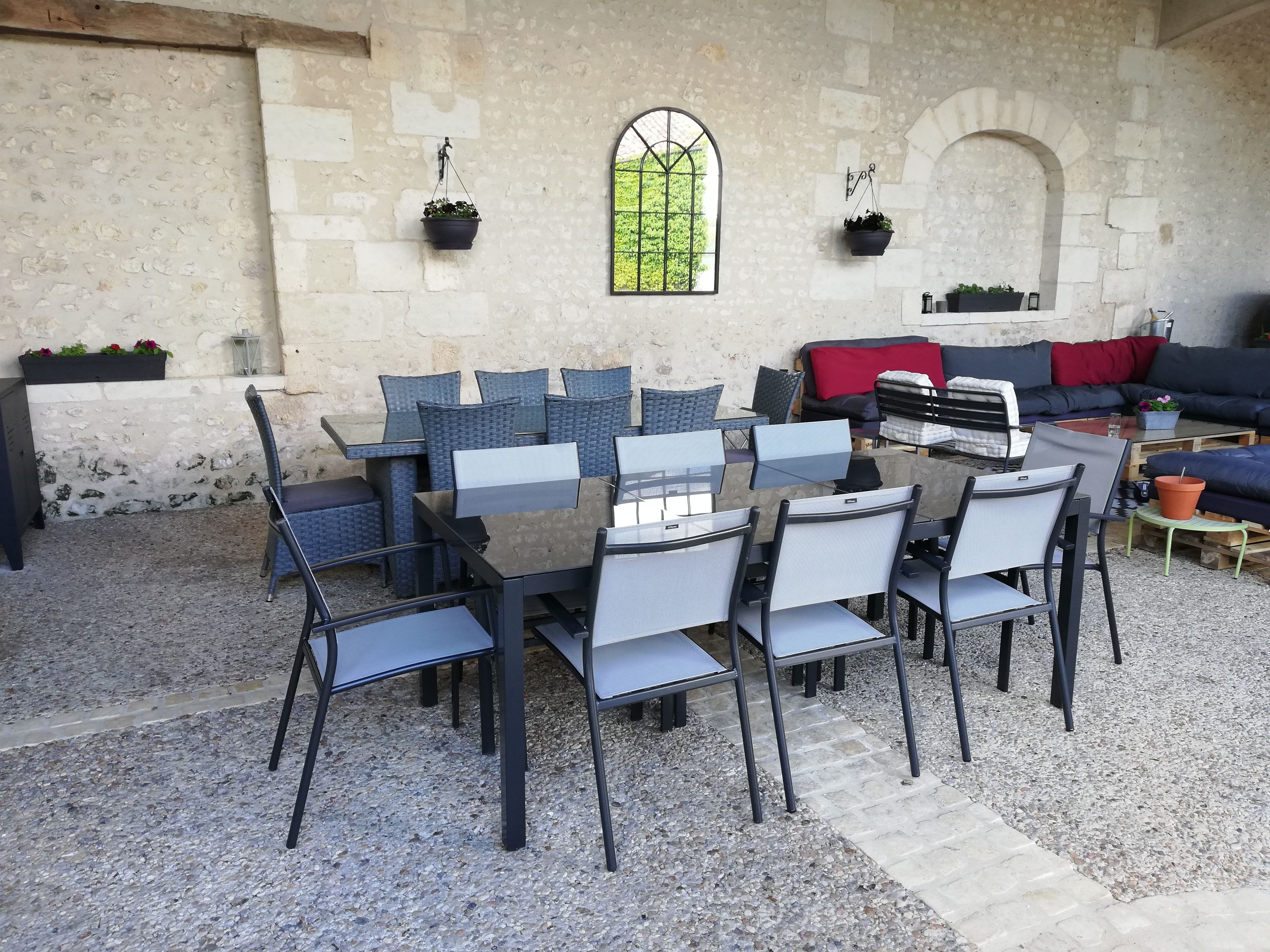 An outdoor seating area with a stone wall, a large window, and a sofa.