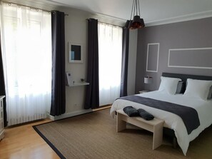 Un dormitorio moderno con una cama grande, mesitas de noche, un banco y una lámpara colgante.